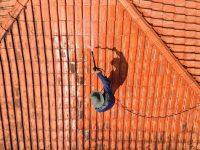 A,Person,Outdoors,Cleaning,The,Red,Clay,Roof,Using,A
